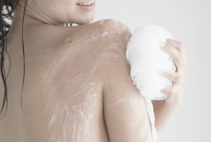 Mujer aplicando jabón corporal con esponja en la ducha. Imagen de uso del jabón Neutro Balance Dermoprotector + Colágeno. Mujer aplicando jabón corporal con esponja en la ducha. Imagen de uso del jabón Neutro Balance Dermoprotector + Colágeno.